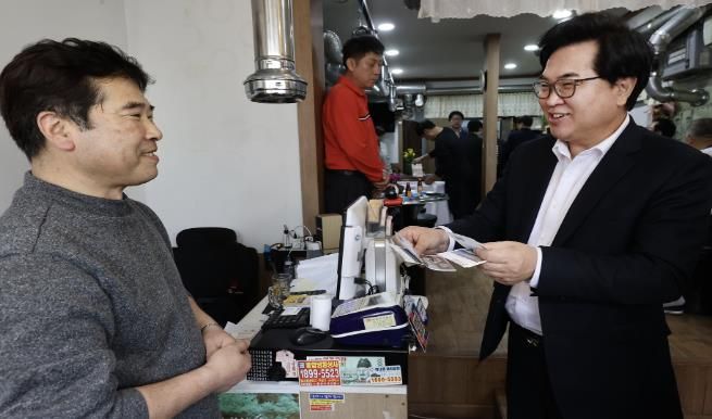 박일하 동작구청장(오른쪽)이 지난 4월 신대방1동 온누리길 골목형 상점가에서 온누리상품권을 사용하고 있다.